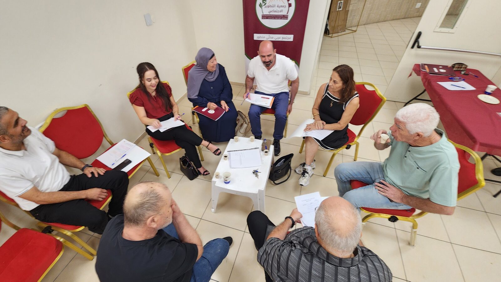 A committee talks in a circle beside SDC's banner, notes and folders in hand.